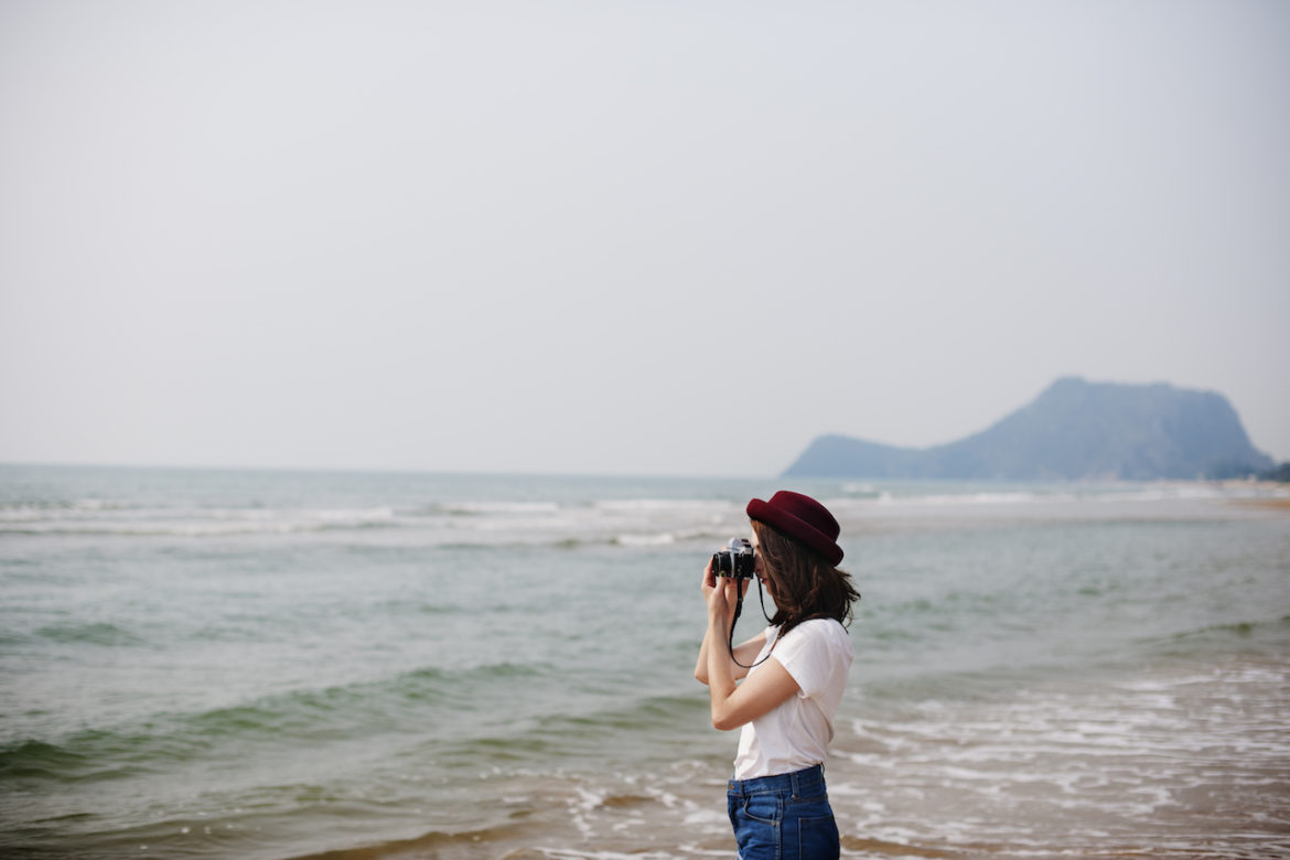 woman striving to pursue the dream with her camera on the beach