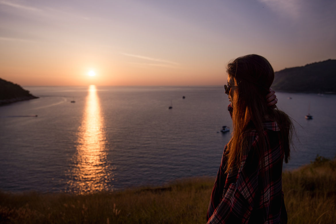 female traveler finds ways to achieve peace by taking an evening stroll at sunset by the sea