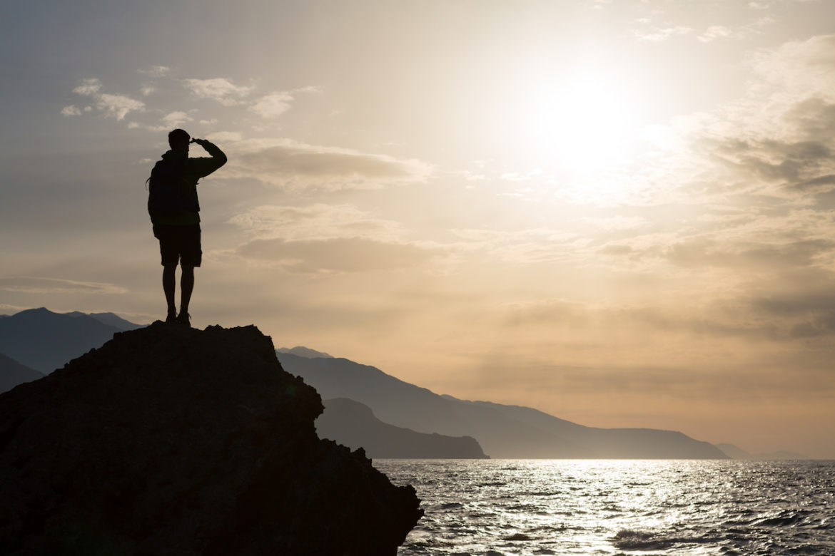 closer to serenity male silhouette looking out to ocean landscape and islands off a rock.