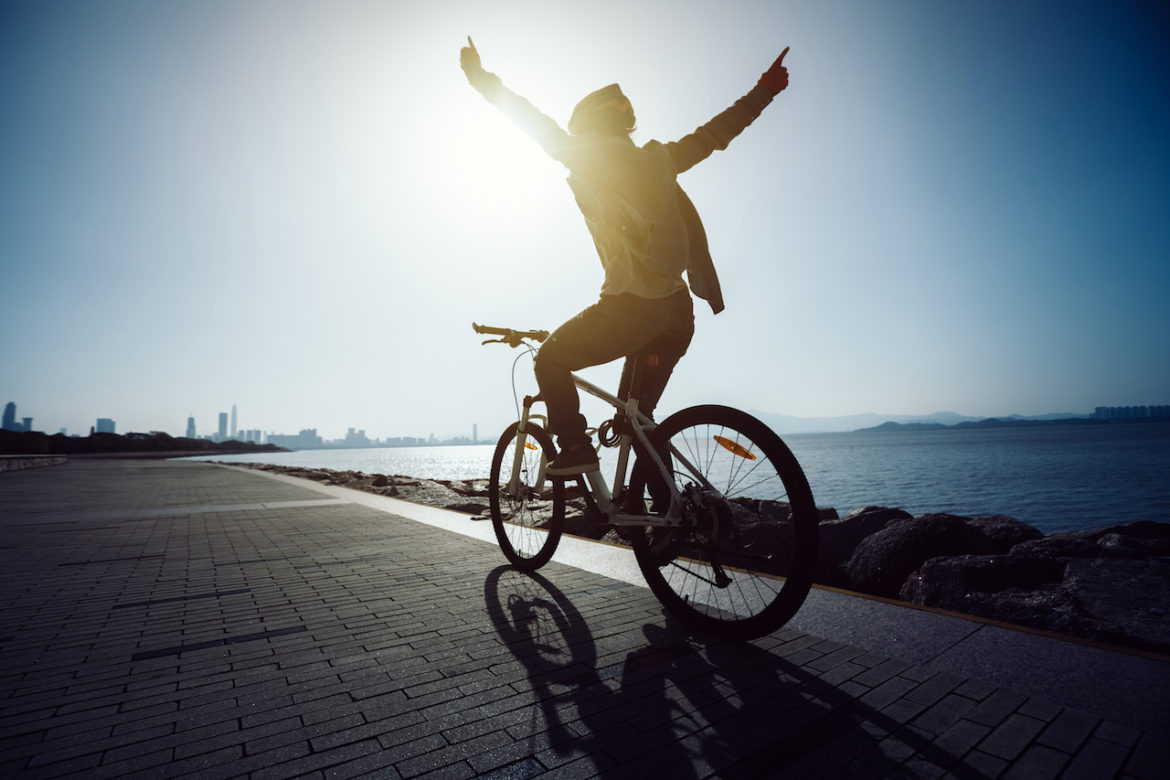 silhouette of cyclist riding toward inner peace along seaside trail at sunrise