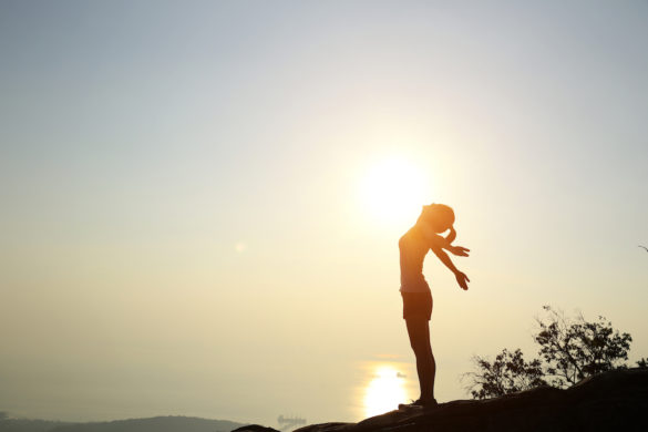 successful-woman-experiences-happiness-on-hilltop-overlooking-the-sea-at-sunset