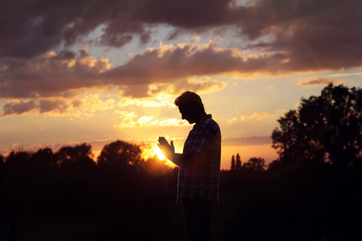 encounter pure love a male silhouette praying outside at sunset