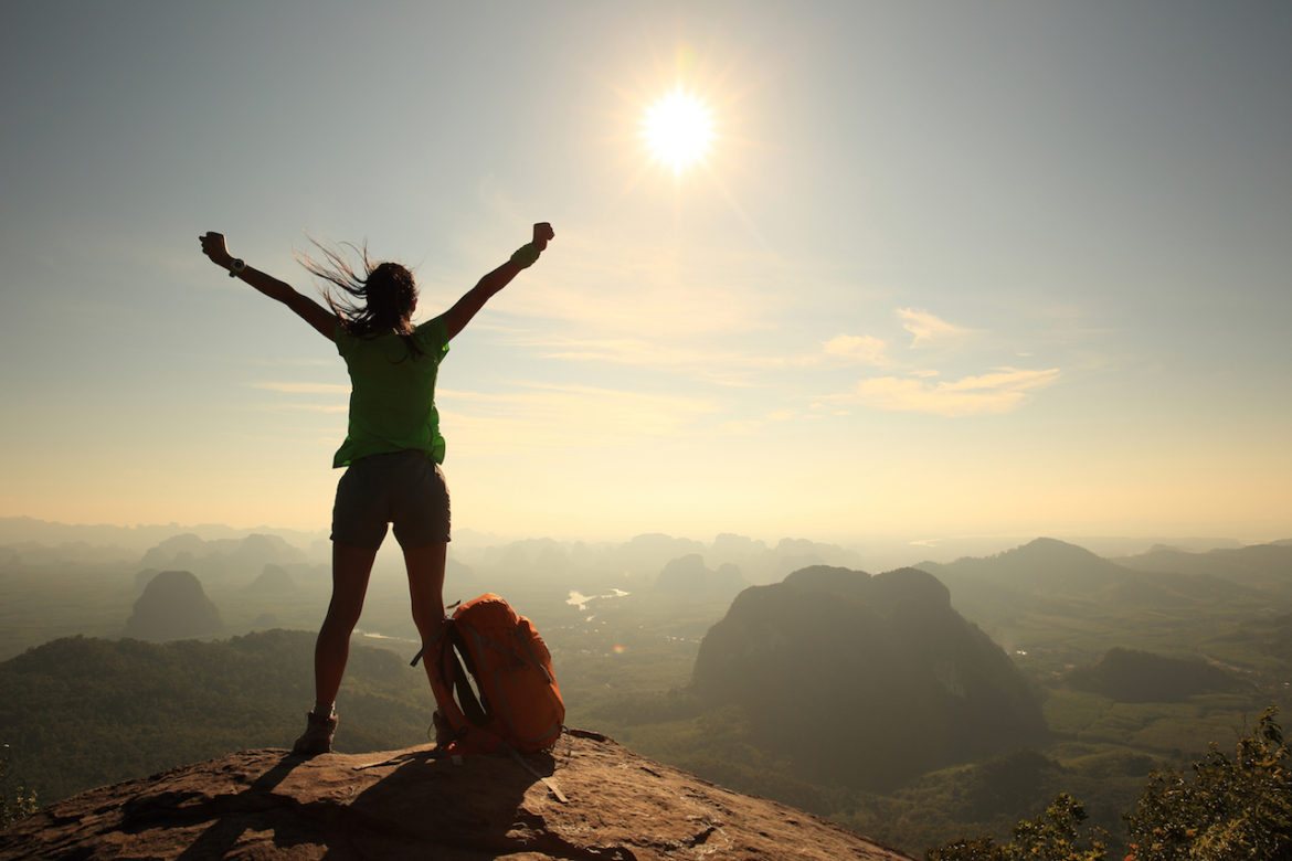 this is now, silhouette of cheering woman hiker open arms on mountain peak at sunrise