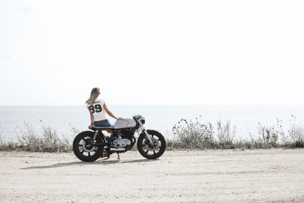 woman chose freedom when given ultimatum my way or the highway on custom cafe racer motorcycle parked facing sunset by the sea