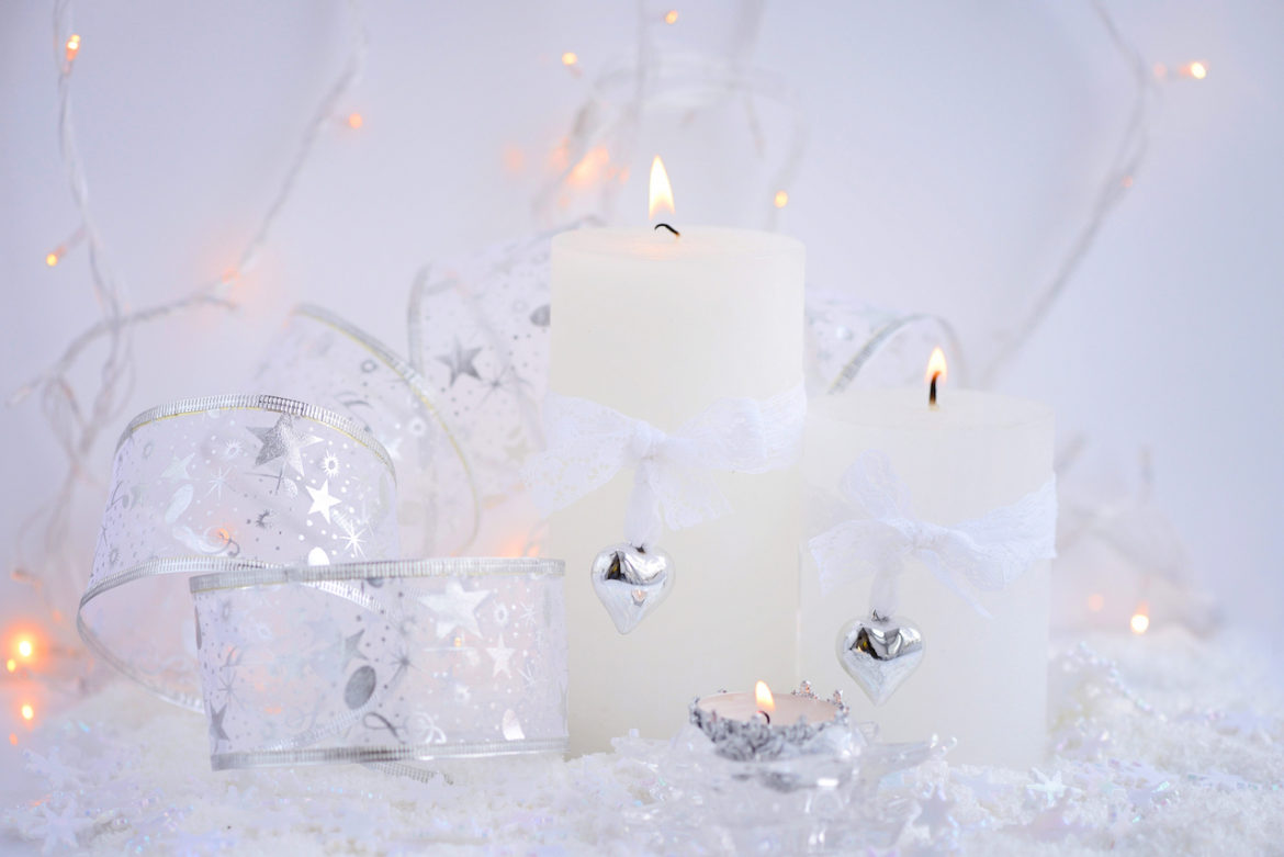 spirit of Christmas with two candles lit each wrapped with lace bows and dangling silver hearts