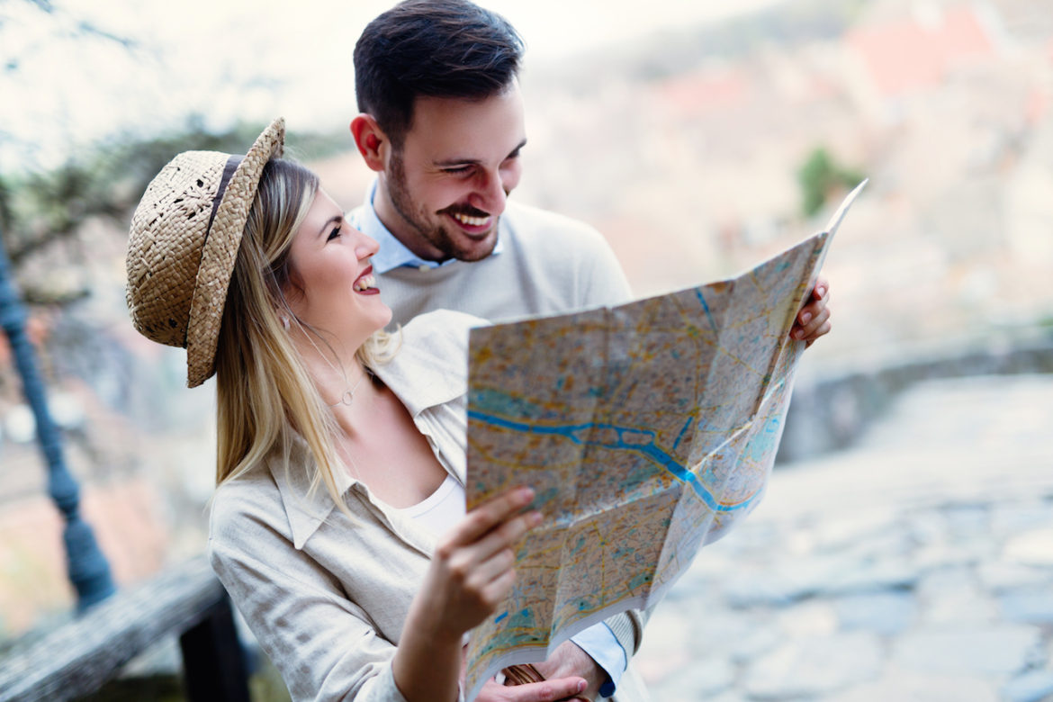live an aspired life couple in love smiling while looking at a map outdoors