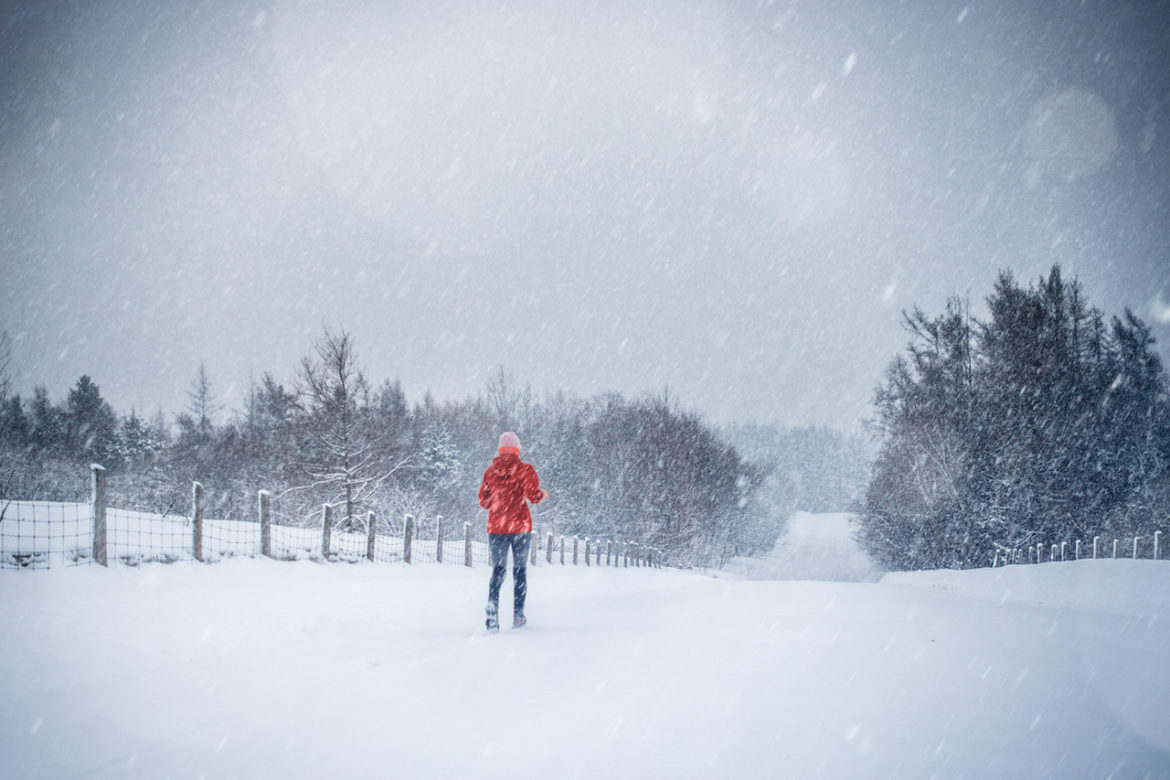 woman running alone in the country to get in shape on a cold snowy day in winter
