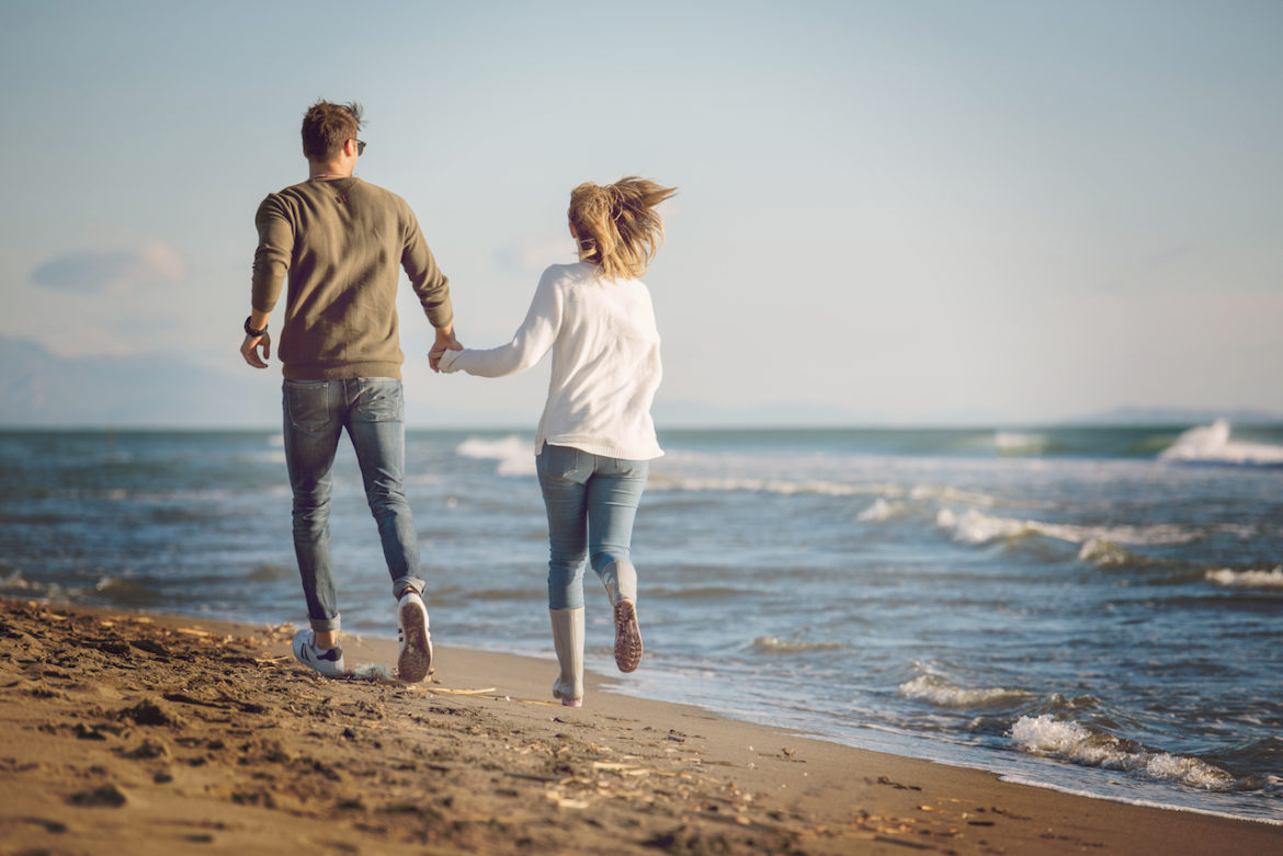 couple in love walk on a beach in autumn holding hands