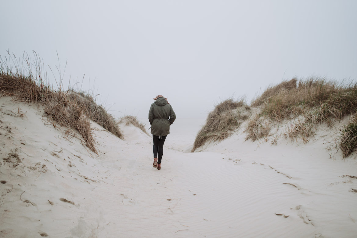 woman walking on a cold overcast winter day at the beach alone after disappearing act