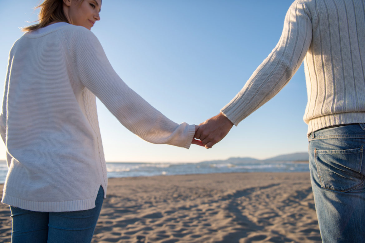 couple take final walk together at the beach on a sunny day in fall before the ghosting