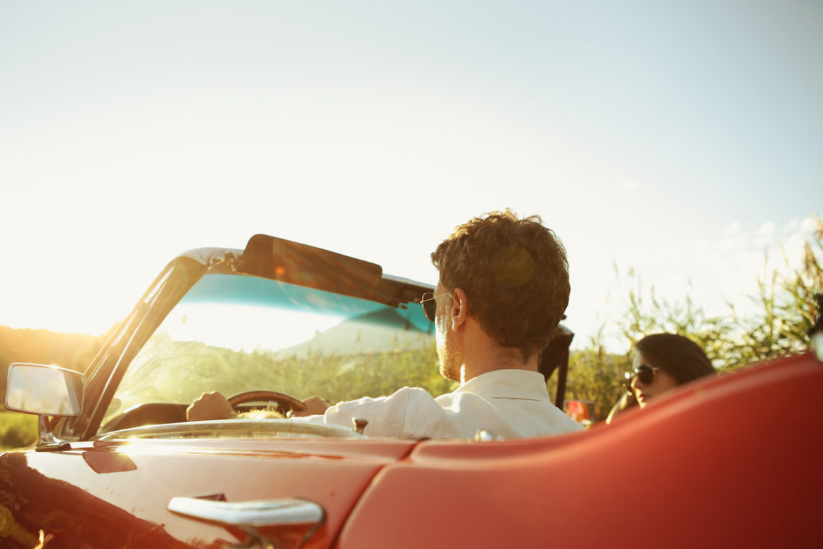 couple stuck in a bad relationship during a road trip in a red convertible along a scenic route on a summer day.