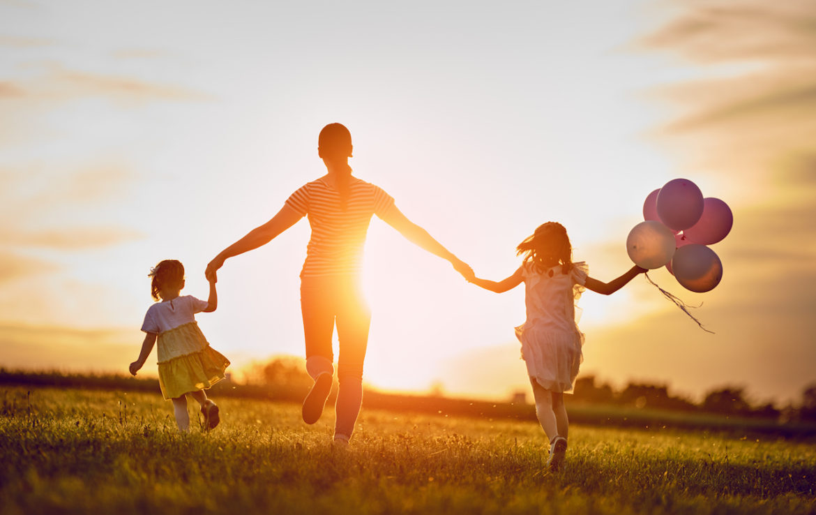 enjoying last month of summer knowing seasons change mother and two daughters hold hands playing on a meadow at sunset