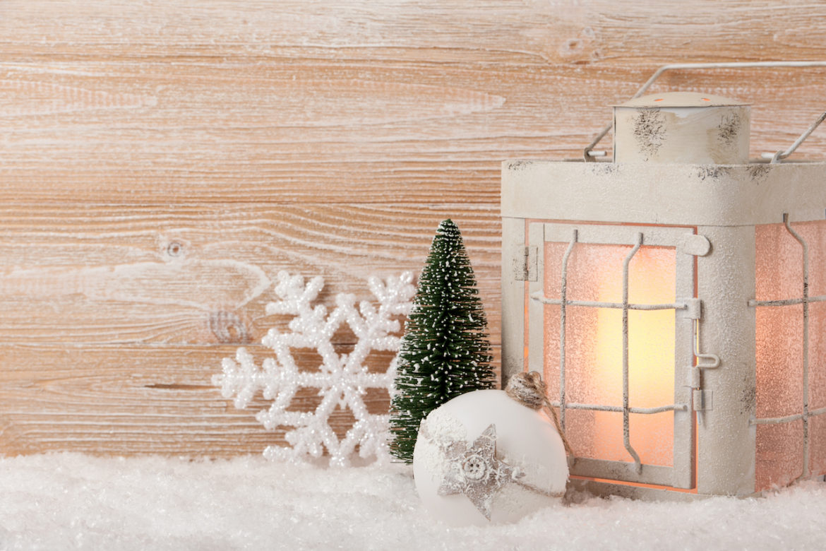 keepsakes of Christmas decorate a background with a lit lantern and a trio of ornaments