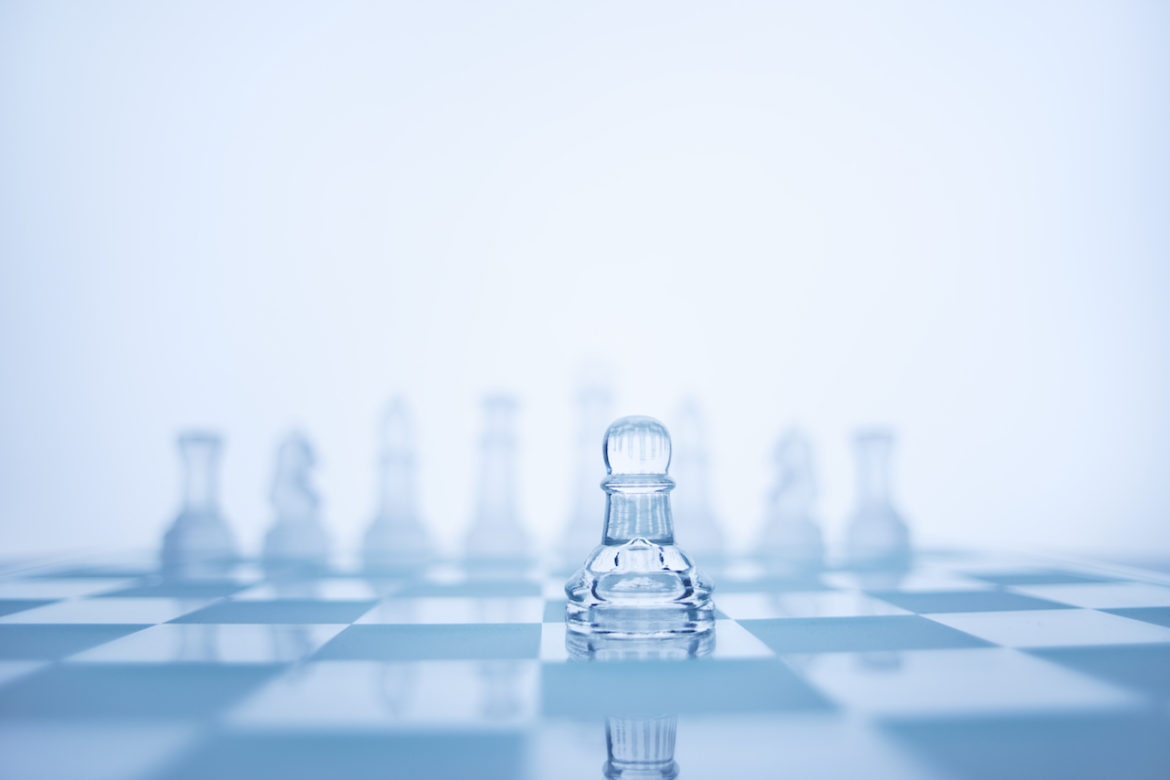 A pawn standing in front of the rest on a chess set depicts the importance of social-distancing.