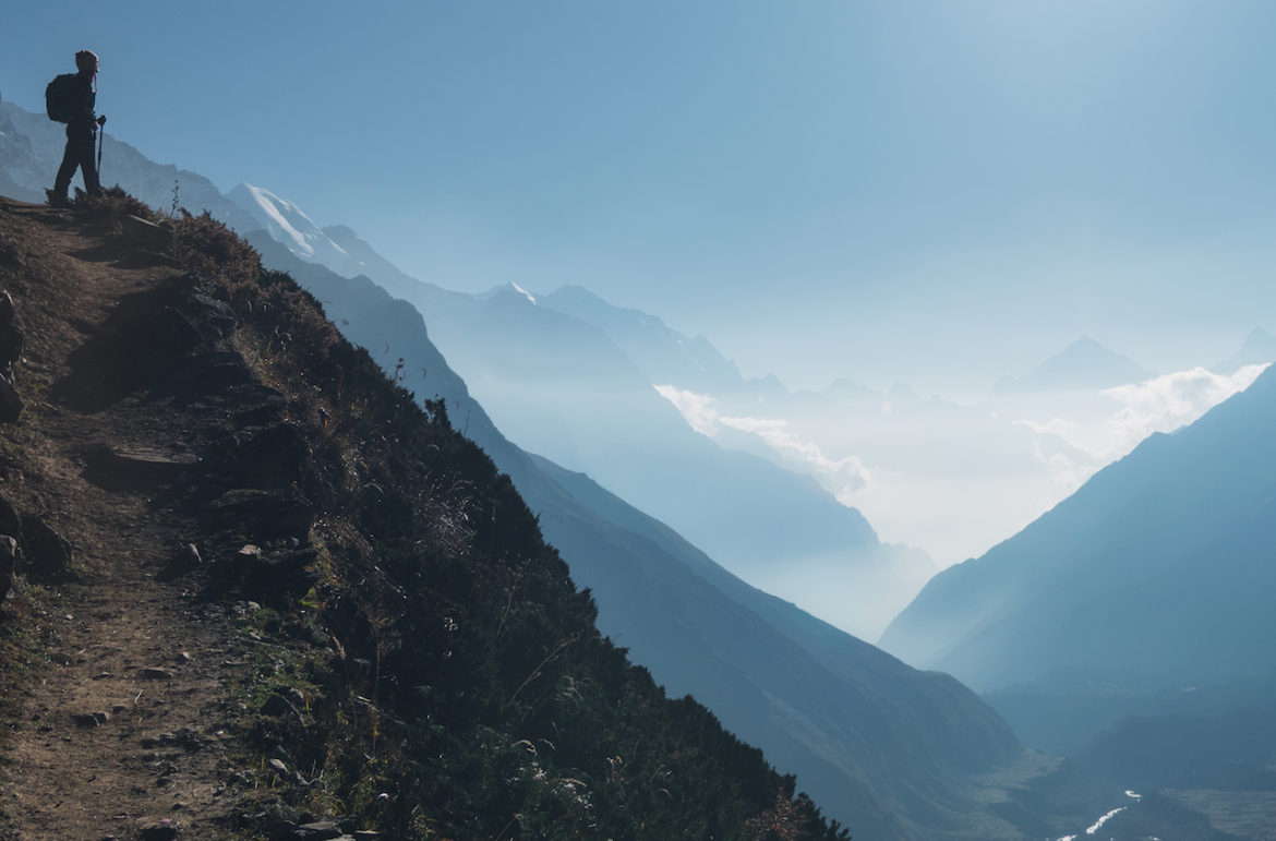 Trekking in Himalayas young woman making better life choices looking out from hilltop in Nepal at sunrise