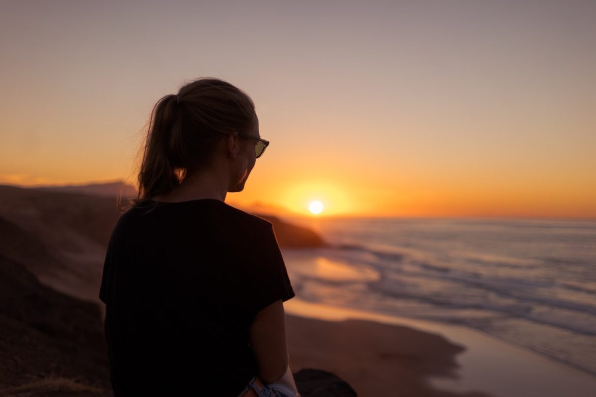 Living your best life is making time for what matters as with this woman by the beach at sunset looking off into the distance