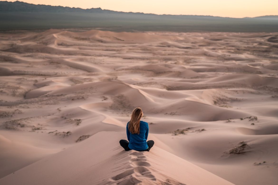 In the desert woman seated on sand looking out toward the hills stuck in never never land