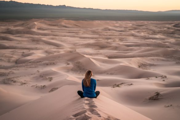 In the desert woman seated on sand looking out toward the hills stuck in never never land