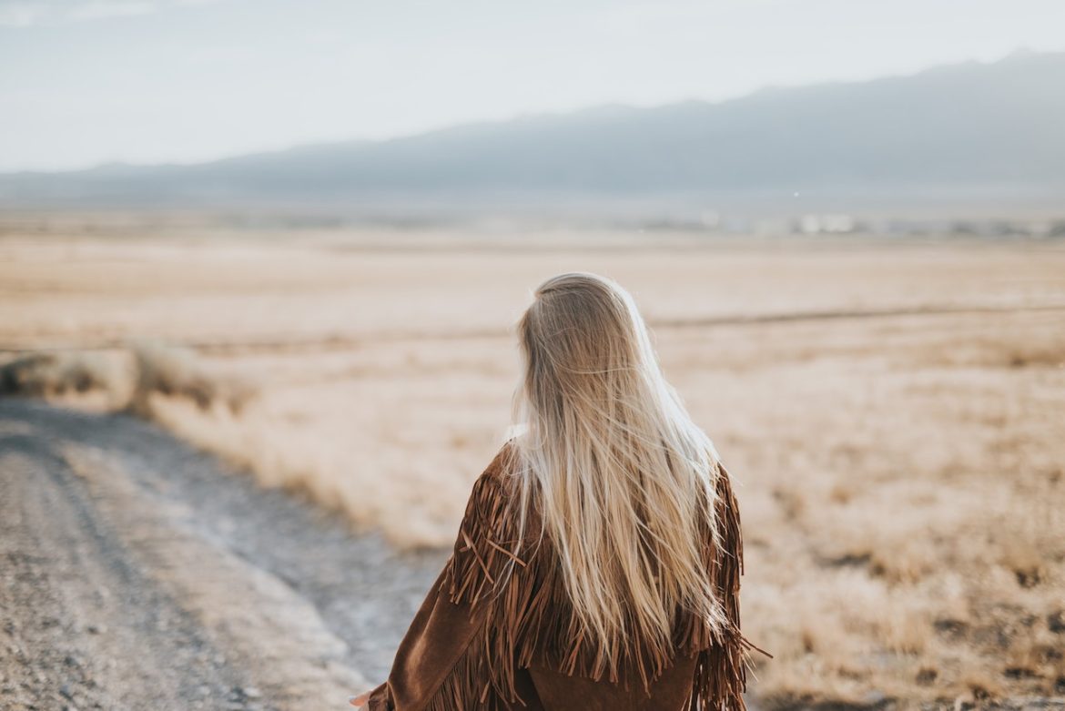 Woman looks down a prairie gravel road contemplating whether settling somewhere between on-again off-again relationship is a bad idea