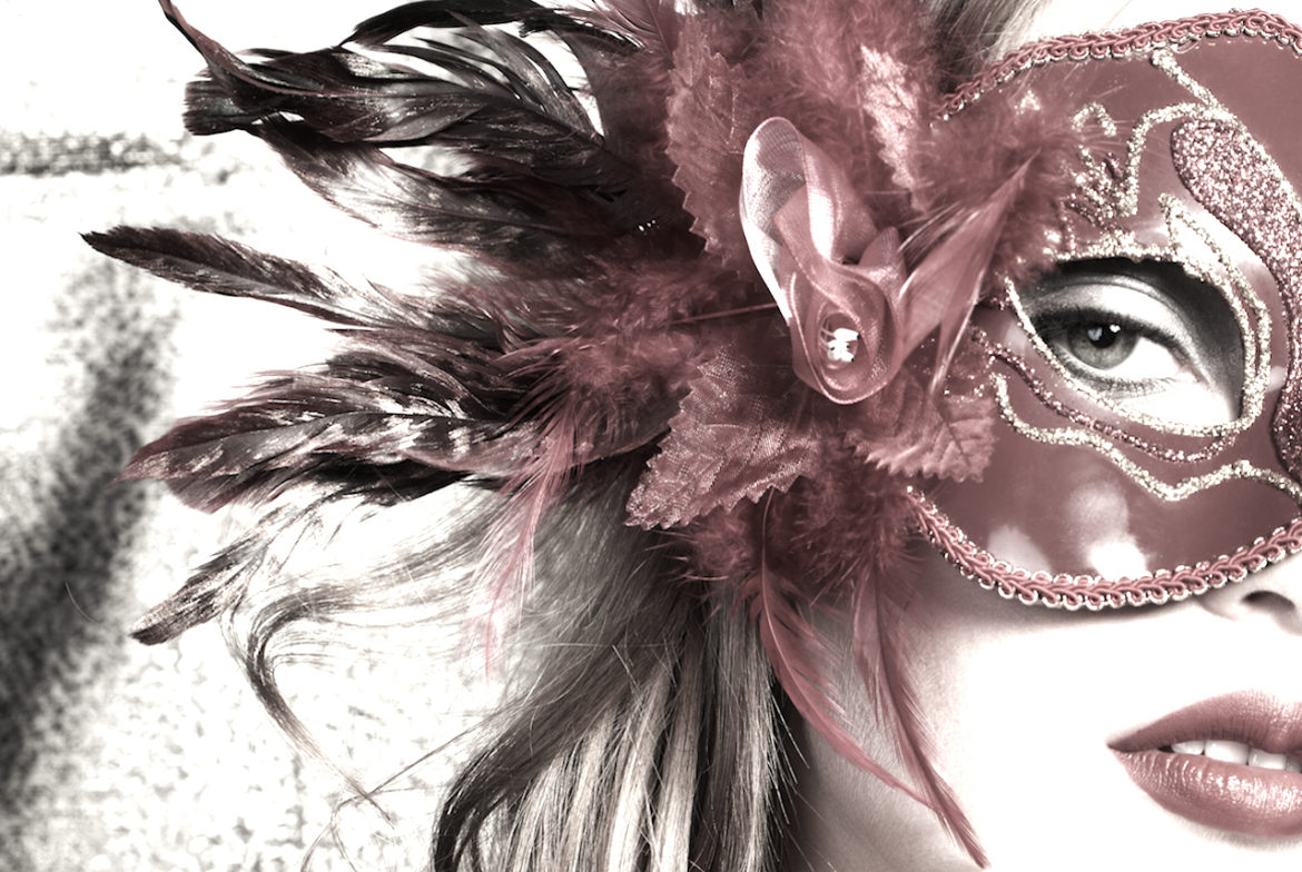 Woman attending a dare to be you masquerade wearing a pale rose venetian mask embossed with glitter and adorned with a silk rose, leaves, and feathers