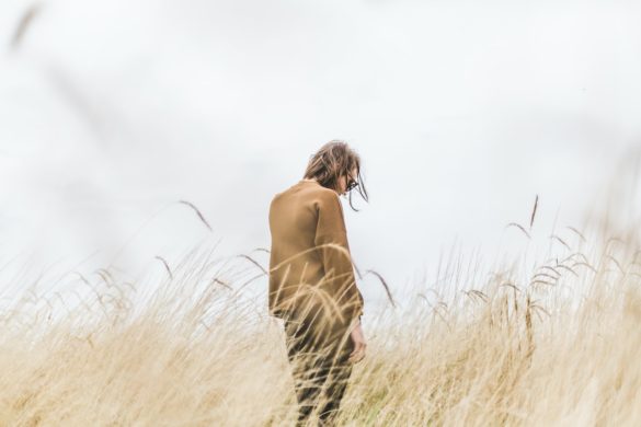woman overcomes-emotional-baggage-on an overcast day amid the golden tall grass