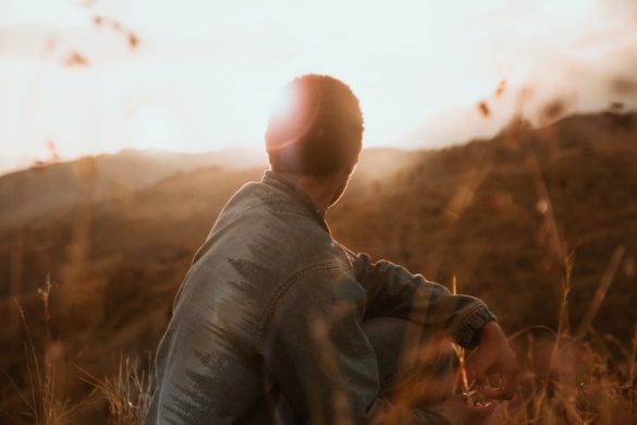 man sitting in a field looking at the sun set on a cool autumn day regretting he was lost for words