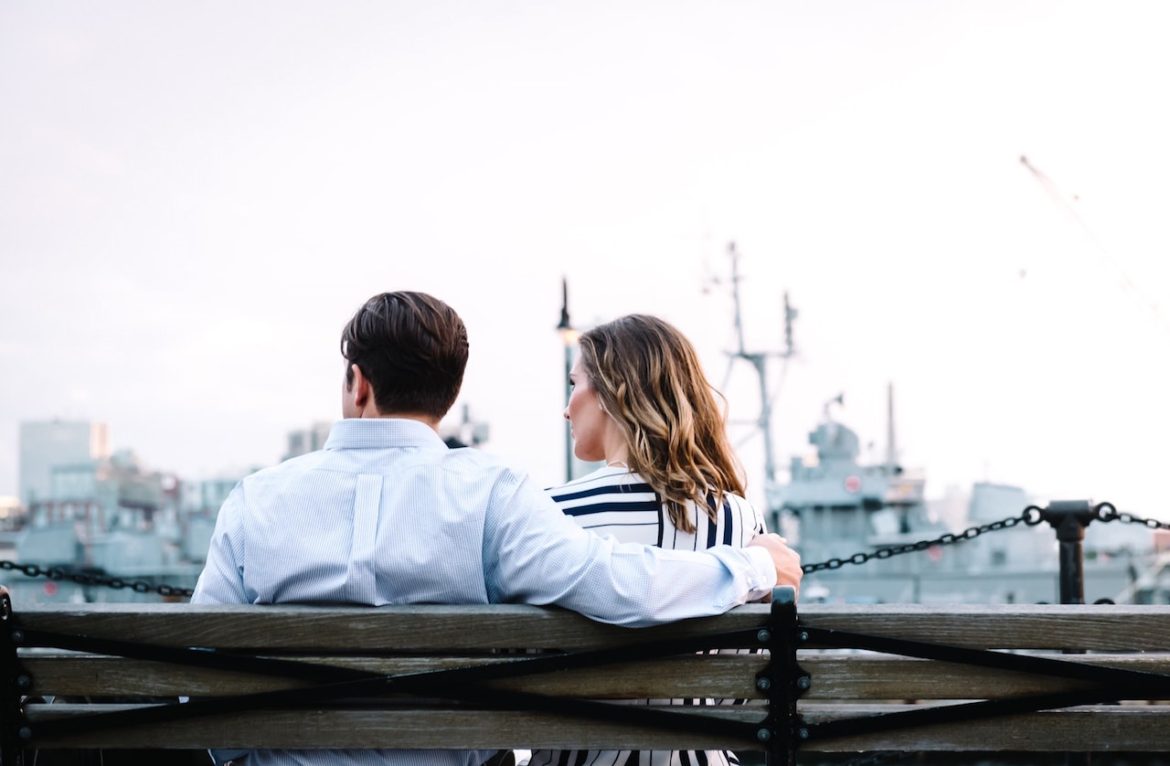 Couple at a harbor seated on a bench looking out into the distance knowing relationships can't be forced only nurtured