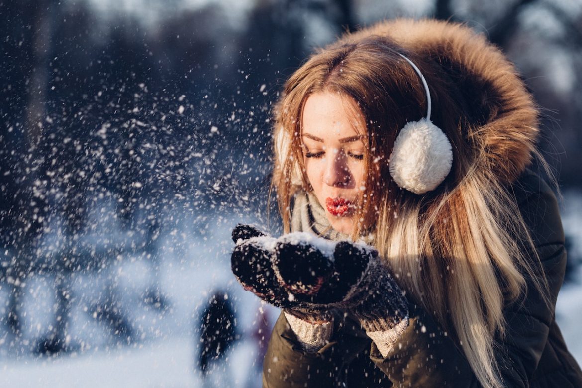 Enjoy the simple things is this young lady's mantra as she blows a hand full of snow off her mitts on a sunny day at the park