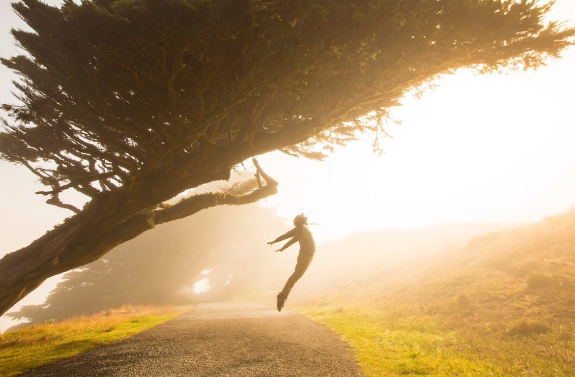 Photo captures a person on a bright day taking a leap of freedom on a pebble path knowing the power of choice lives in the magic of now