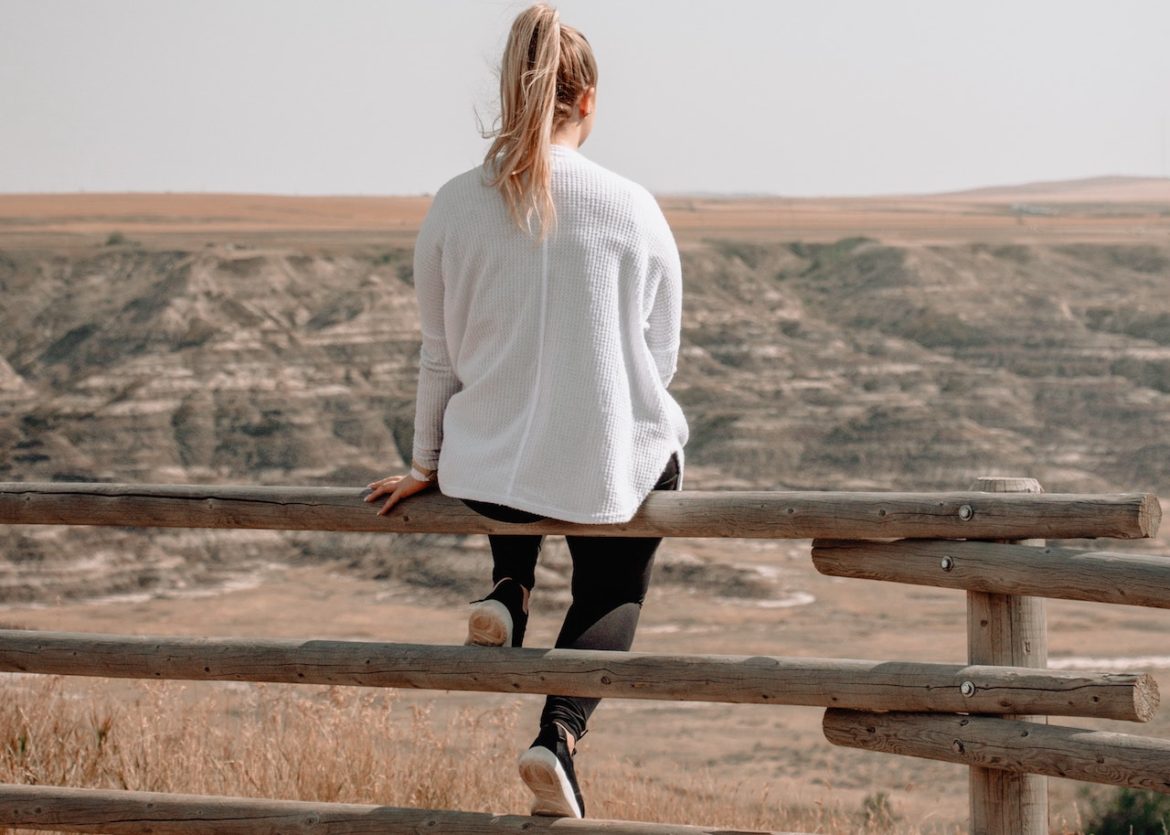 Woman on the fence on a sunny day looking off into the distant plains knowing it's time for making the best choices