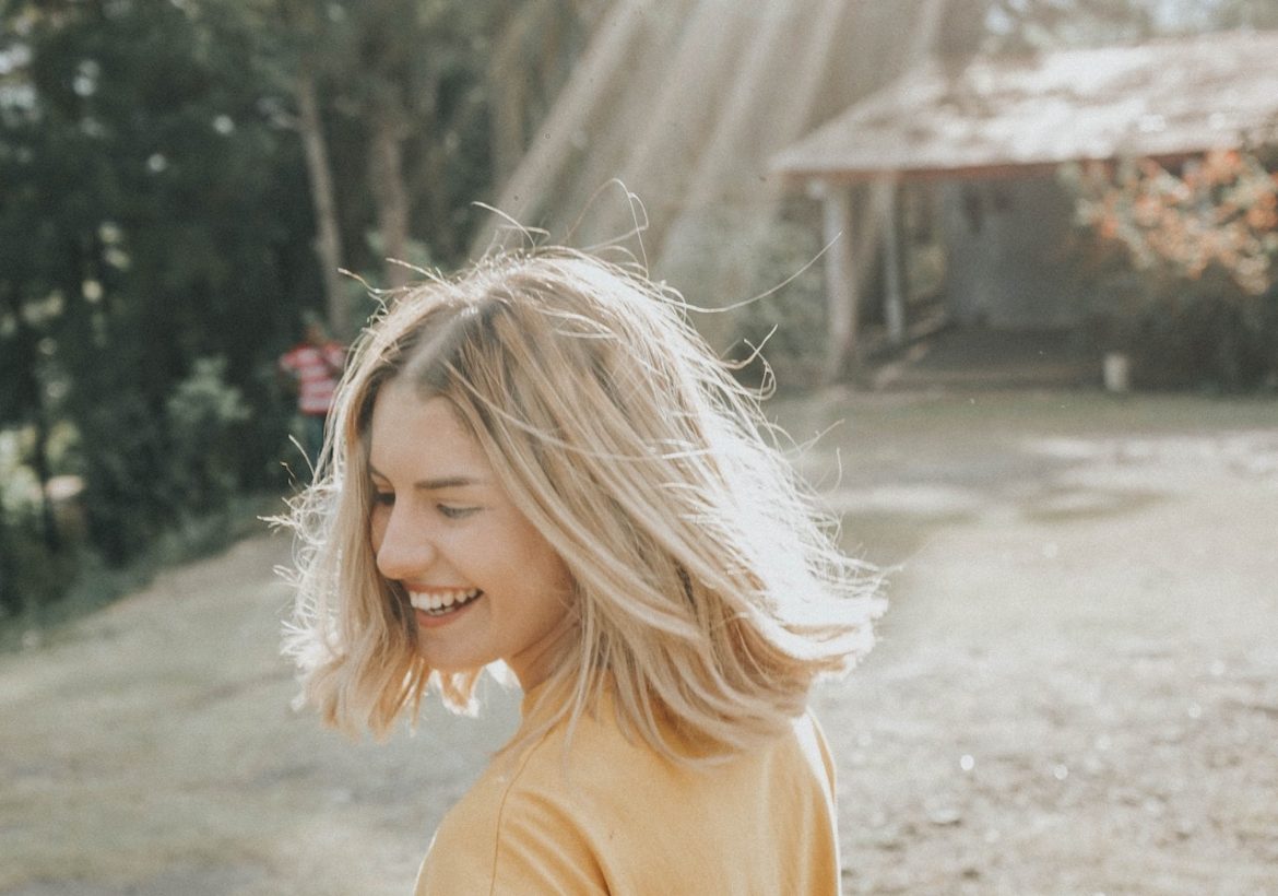 Rays of sunshine lights up a happy face of a young woman who lives by the motto you already know your happiness is a choice