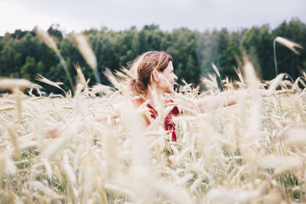 Woman in a wheat field, basking in the sun's glow on the road to decisiveness.