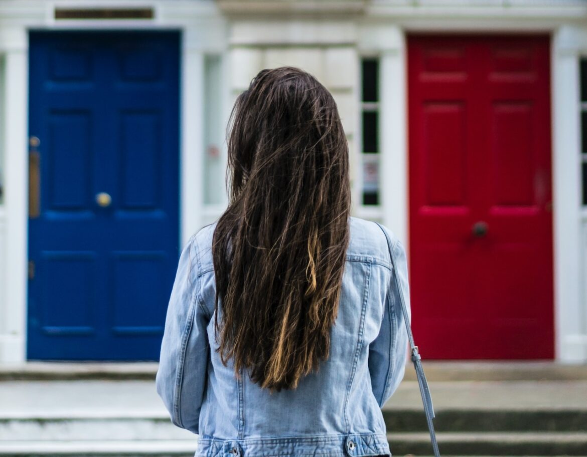 She stands before a blue door and a red door, deciding who's the right person, wrong person.