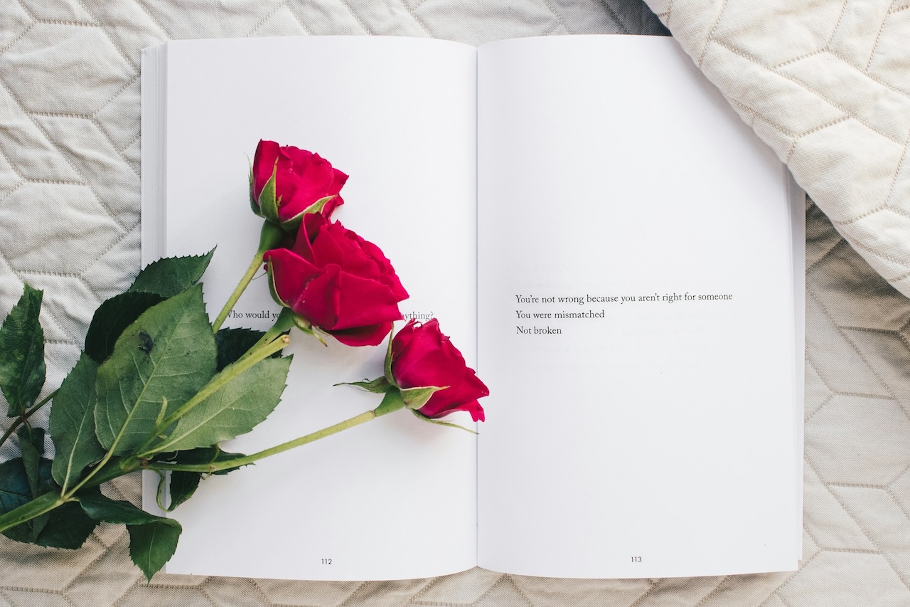 Three red roses sit on an open book revealing that your guide in overcoming confusion is to keep it real